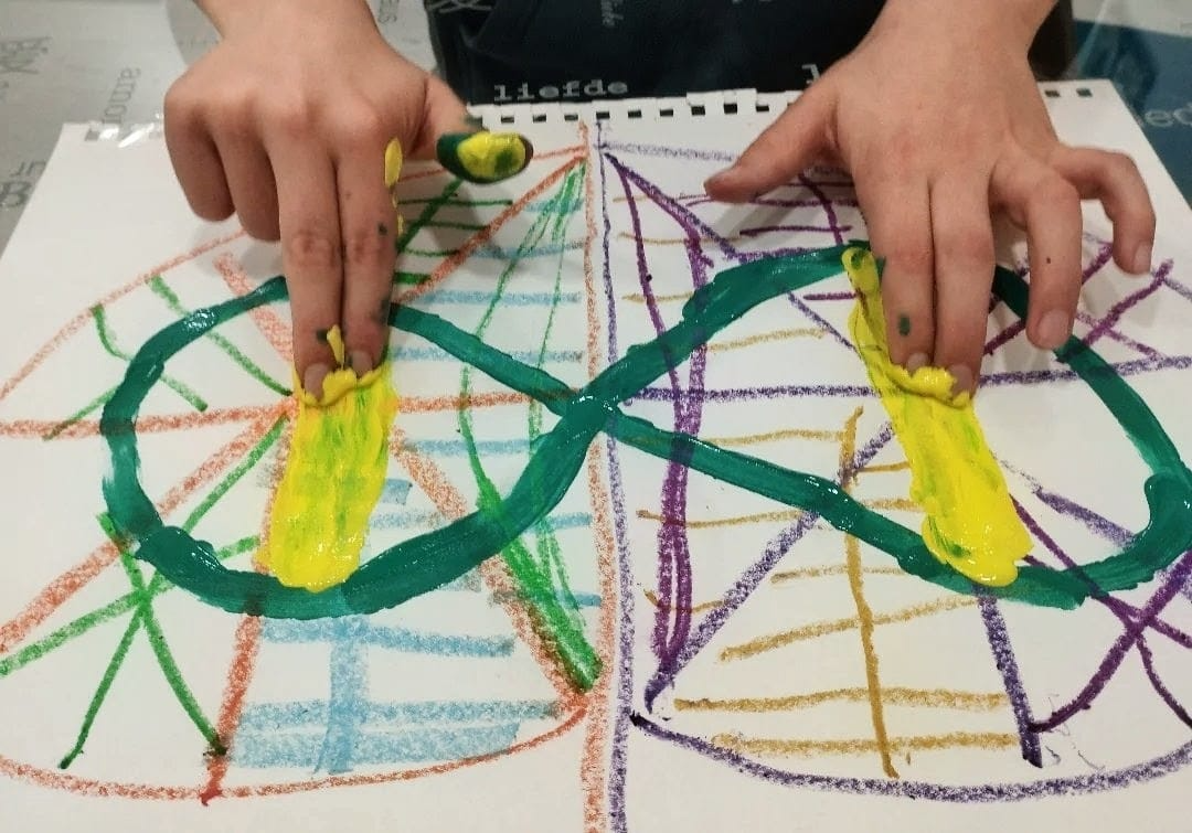 Mains d'enfants créant ensemble une œuvre à la peinture et aux crayons